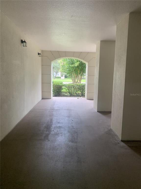 A covered concrete carport features an arched entryway looking out toward a landscaped yard — 280 CELEBRATION BOULEVARD UNIT 27104, CELEBRATION, FL