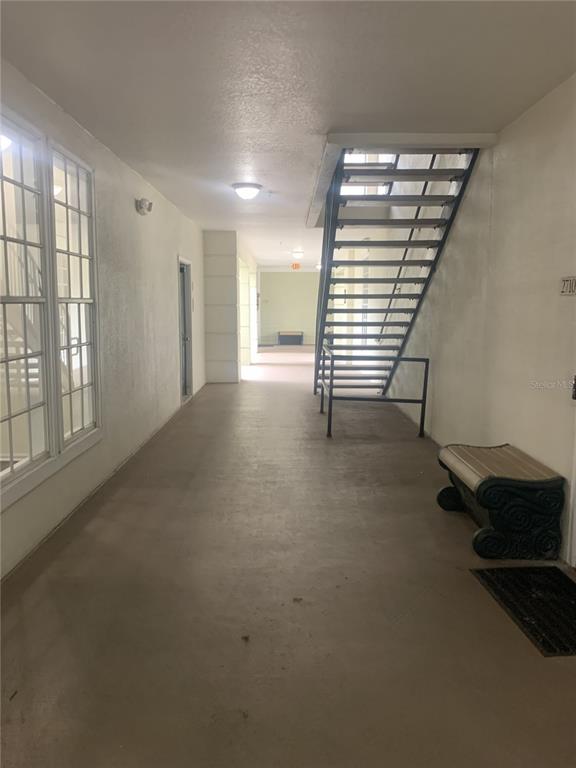An outdoor apartment corridor features a metal staircase, a bench, and a concrete floor — 280 CELEBRATION BOULEVARD UNIT 27104, CELEBRATION, FL