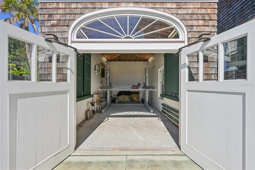 An open garage with a car lift, shingle siding, and a large arched transom window — 178 AVENIDA MENENDEZ, ST AUGUSTINE, FL