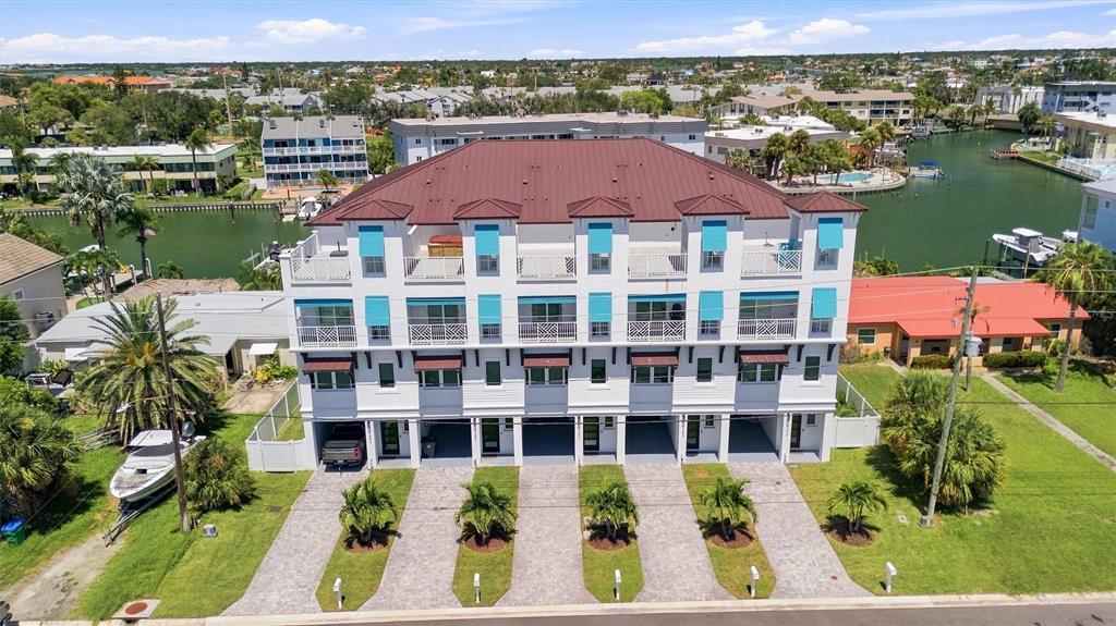An aerial view of a multi-story white residential building with a brown roof near water — 11797 1ST STREET E, TREASURE ISLAND, FL