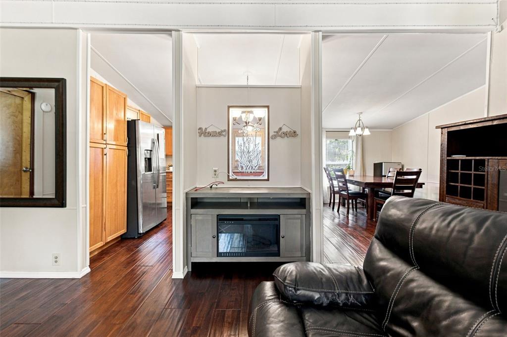 A living room with wood flooring, a fireplace console, and an adjacent dining area — 7608 W OTTER STREET, HOMOSASSA, FL