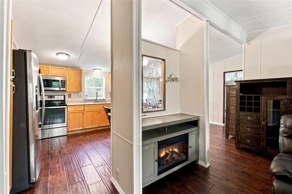 A view from a living area looking into a kitchen with wood-look flooring and cabinets — 7608 W OTTER STREET, HOMOSASSA, FL