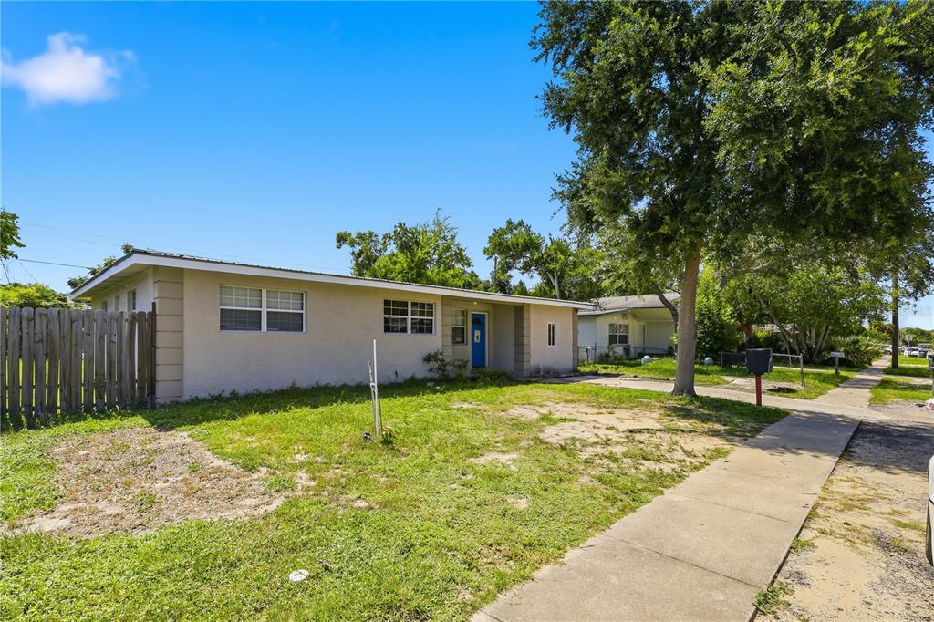 A single-story house with a blue front door, a wooden fence, and a large tree — 934 LEWIS DRIVE, DAYTONA BEACH, FL