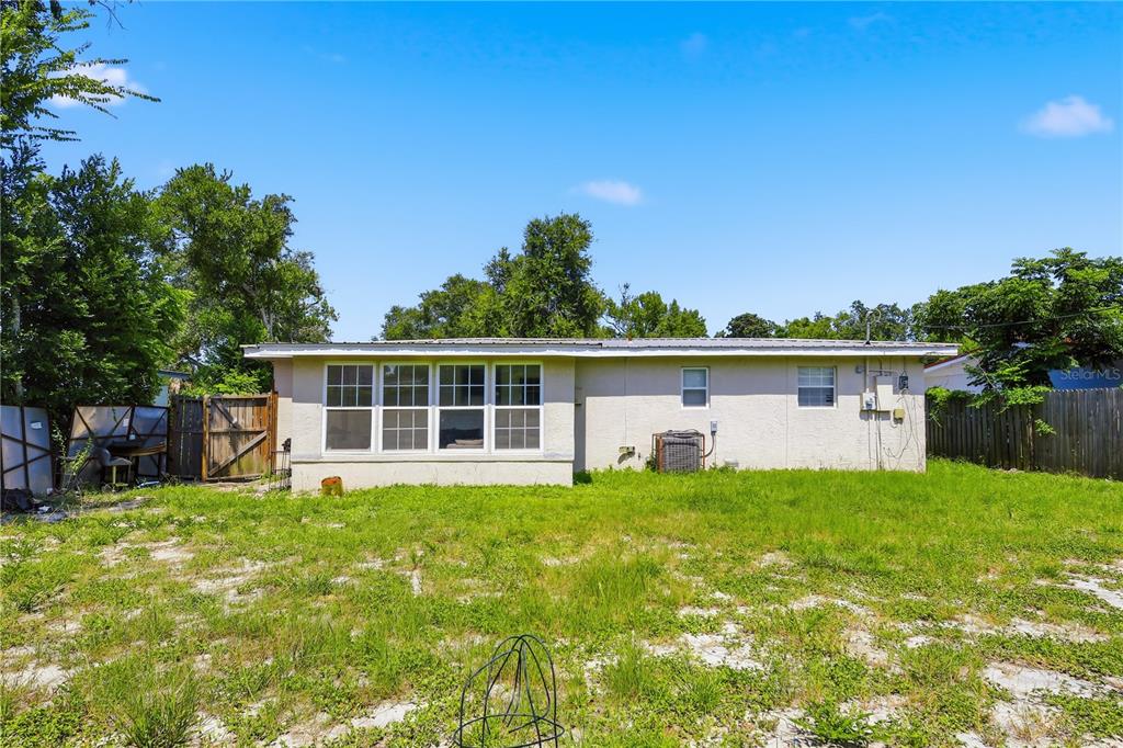 The exterior of a single-story house with a light-colored stucco finish and a grassy yard — 934 LEWIS DRIVE, DAYTONA BEACH, FL