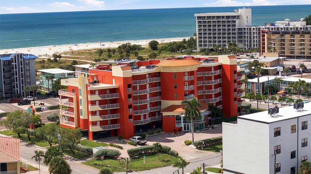 An aerial view of a multi-story green hotel building near a sandy beach and ocean — 11605 GULF BOULEVARD UNIT 402, TREASURE ISLAND, FL