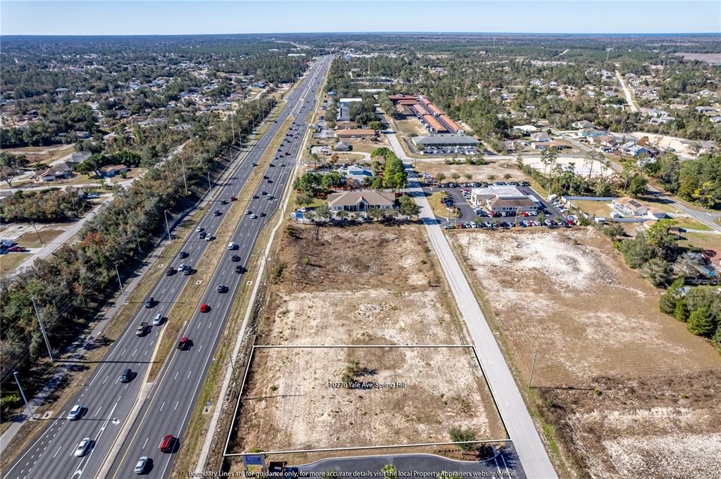 An aerial view shows a vacant, rectangular lot situated next to a busy highway — 10270 YALE AVENUE, WEEKI WACHEE, FL