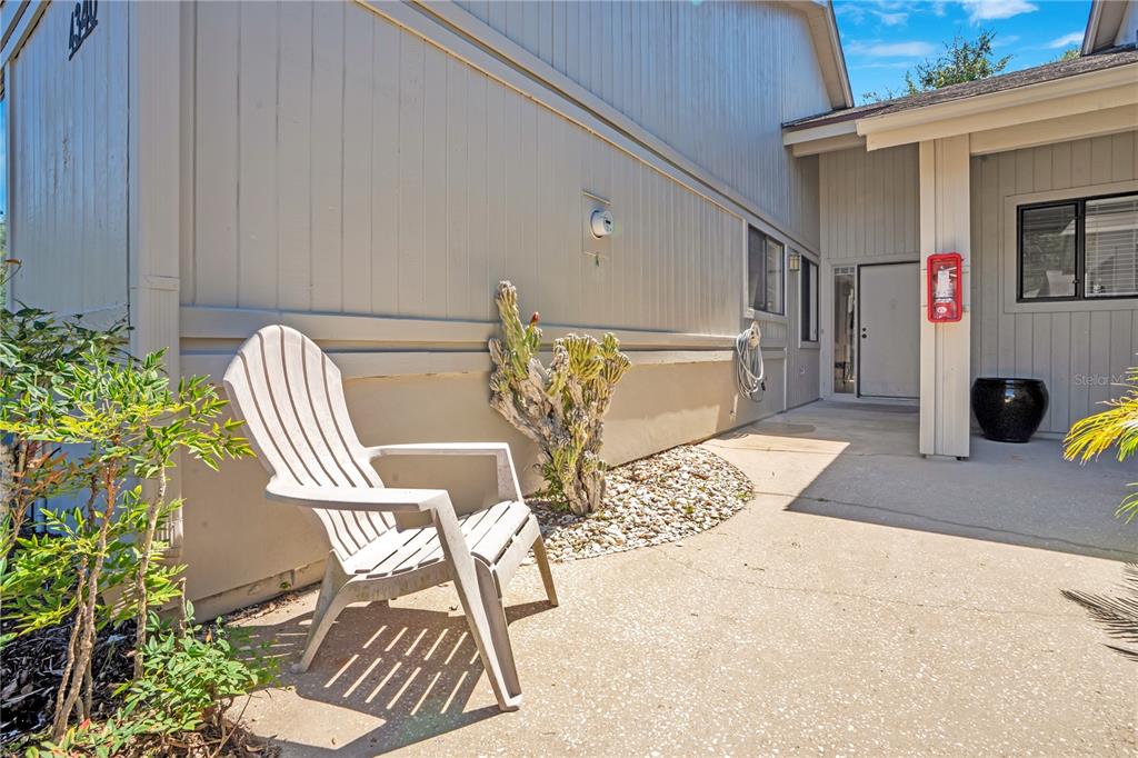 A single-story building with beige siding, a shingled roof, and a paved walkway to the entrance — 4340 SEA MIST DRIVE, NEW SMYRNA BEACH, FL