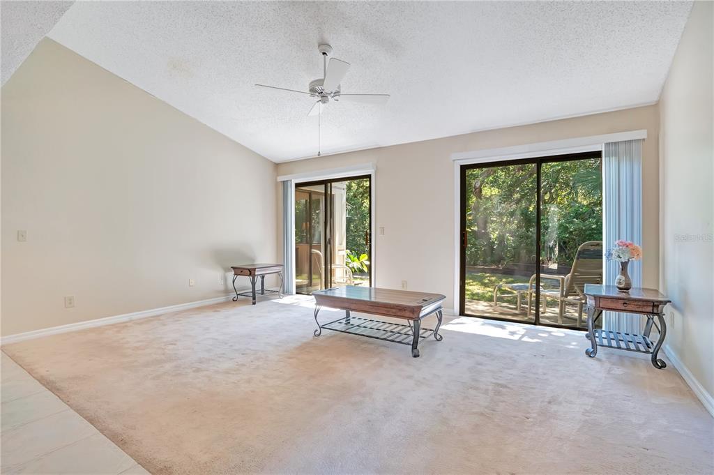 A dining area with tile flooring transitions into a carpeted living room with vaulted ceilings — 4340 SEA MIST DRIVE, NEW SMYRNA BEACH, FL