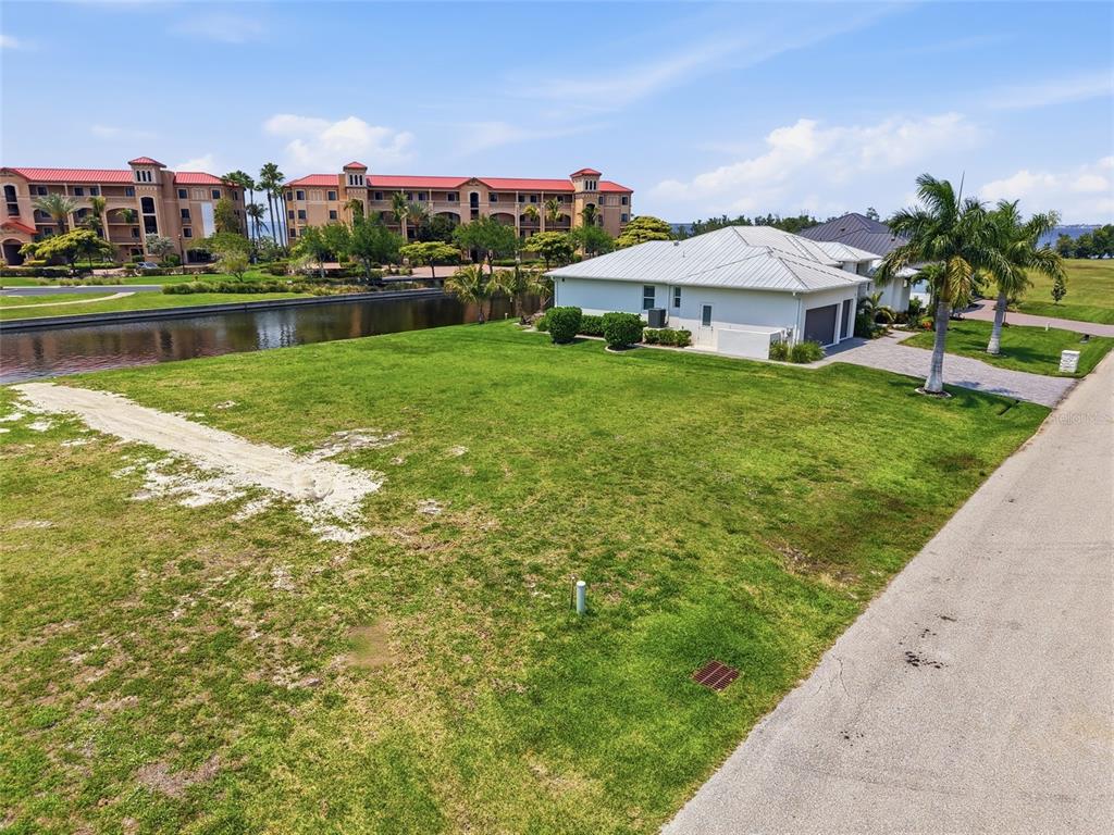 An aerial view shows a vacant grassy lot next to a house and a canal — 81 COLONY POINT DRIVE, PUNTA GORDA, FL