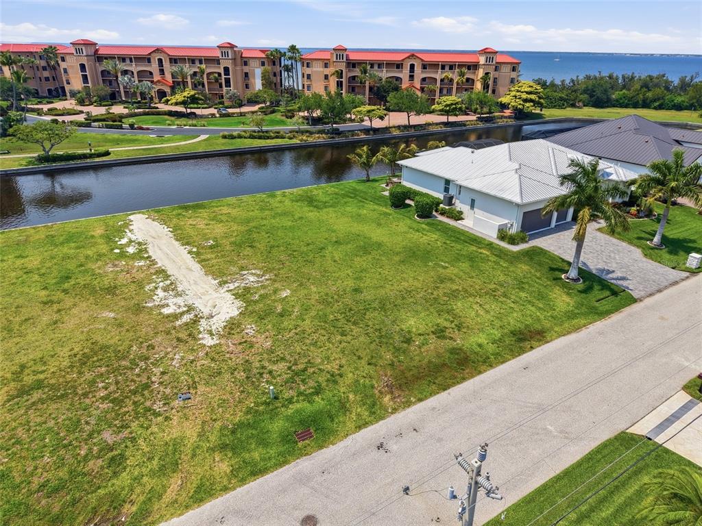 An aerial view shows a vacant grassy lot next to a house by a canal — 81 COLONY POINT DRIVE, PUNTA GORDA, FL