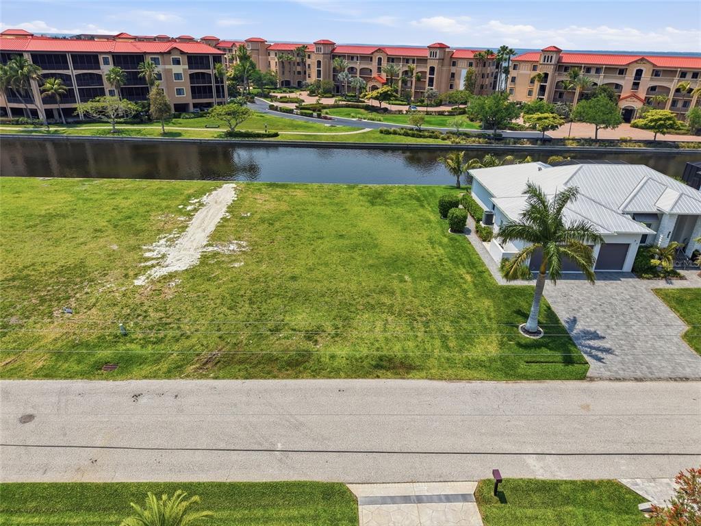 An aerial view shows a vacant grassy lot situated between a house and a canal — 81 COLONY POINT DRIVE, PUNTA GORDA, FL