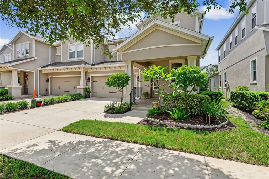 A two-story suburban house with a beige stucco exterior, two garages, and a front porch — 14507 ROCKY BROOK DRIVE, TAMPA, FL