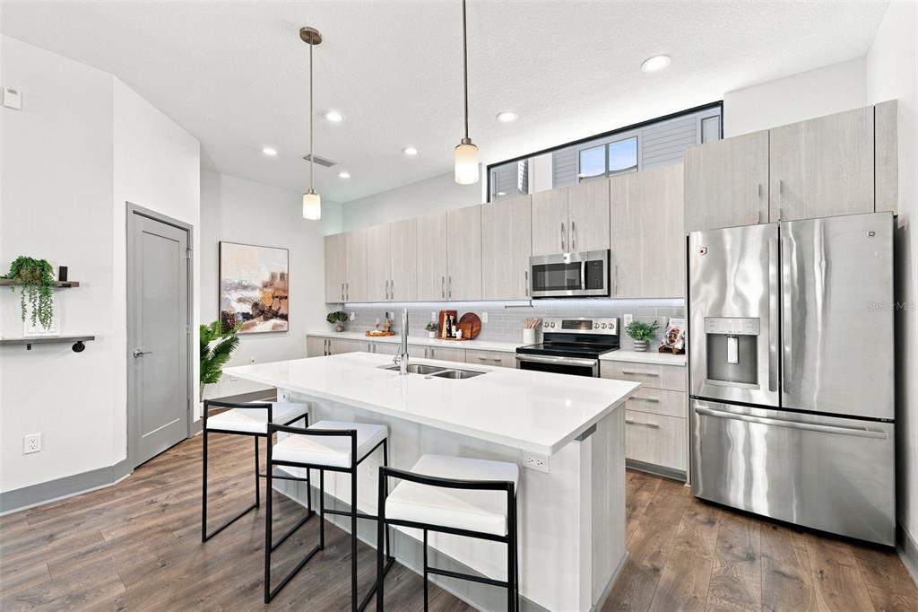 A modern kitchen features light wood cabinets, a white quartz island, and stainless steel appliances — 4810 W MCELROY AVENUE UNIT 3, TAMPA, FL
