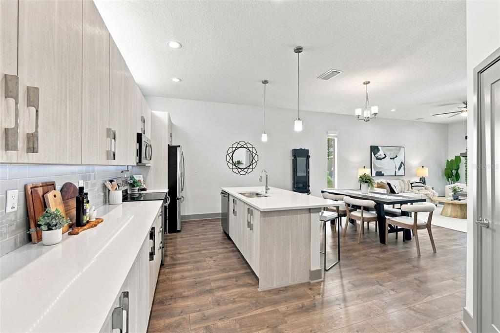 A modern kitchen with light wood cabinets, white countertops, and an island overlooks a dining area — 4810 W MCELROY AVENUE UNIT 3, TAMPA, FL