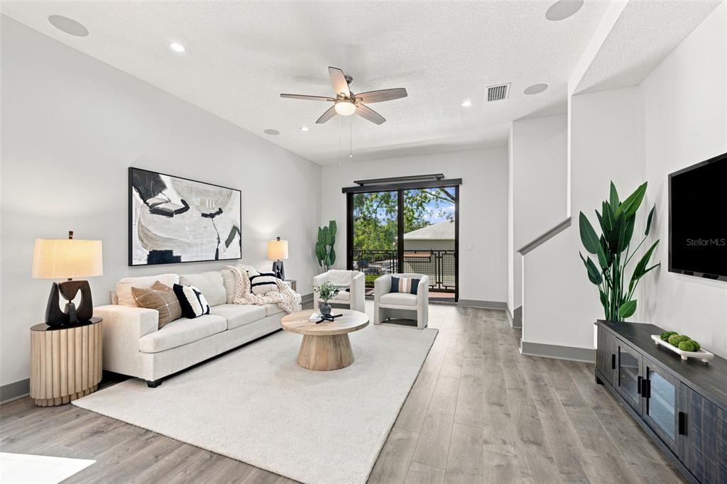 A modern living room features a light-colored sofa, wood coffee table, and sliding glass doors — 4810 W MCELROY AVENUE UNIT 3, TAMPA, FL