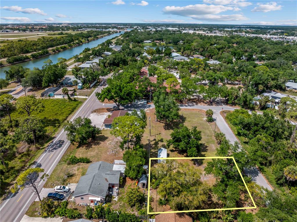 An aerial view shows a vacant, tree-covered lot outlined in yellow near a road — DAWN DRIVE, VENICE, FL