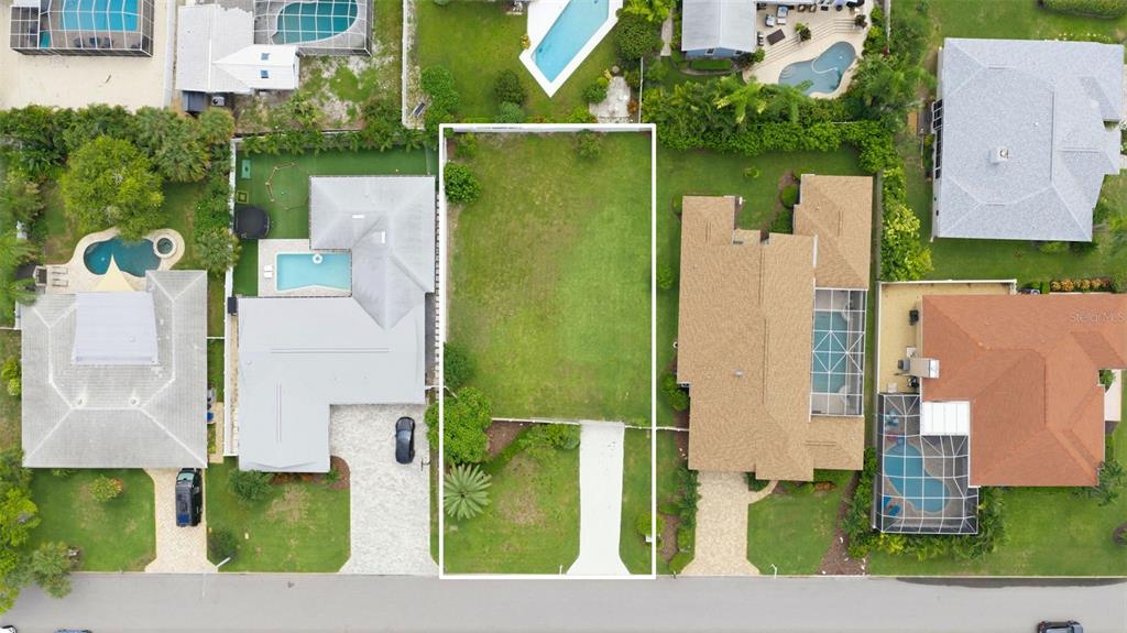 This aerial view shows a vacant residential lot situated between two houses with swimming pools — 343 7TH AVENUE N, TIERRA VERDE, FL
