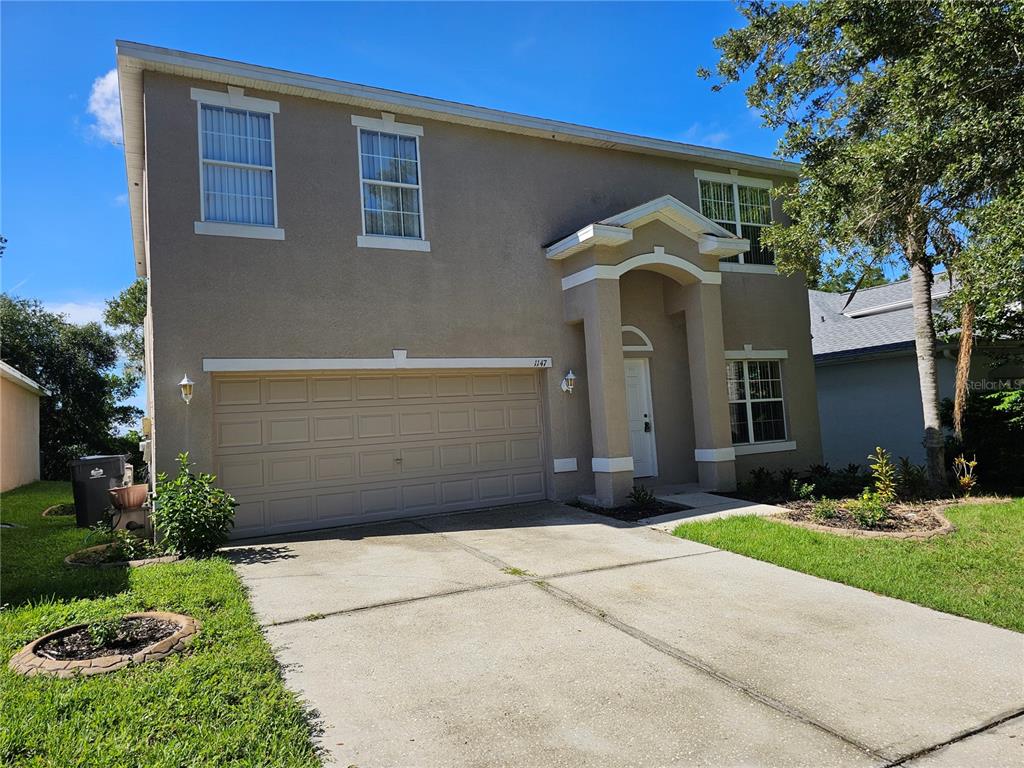 A two-story house with a beige stucco exterior, a two-car garage, and a covered entryway — 1147 EMERALD HILL WAY, VALRICO, FL