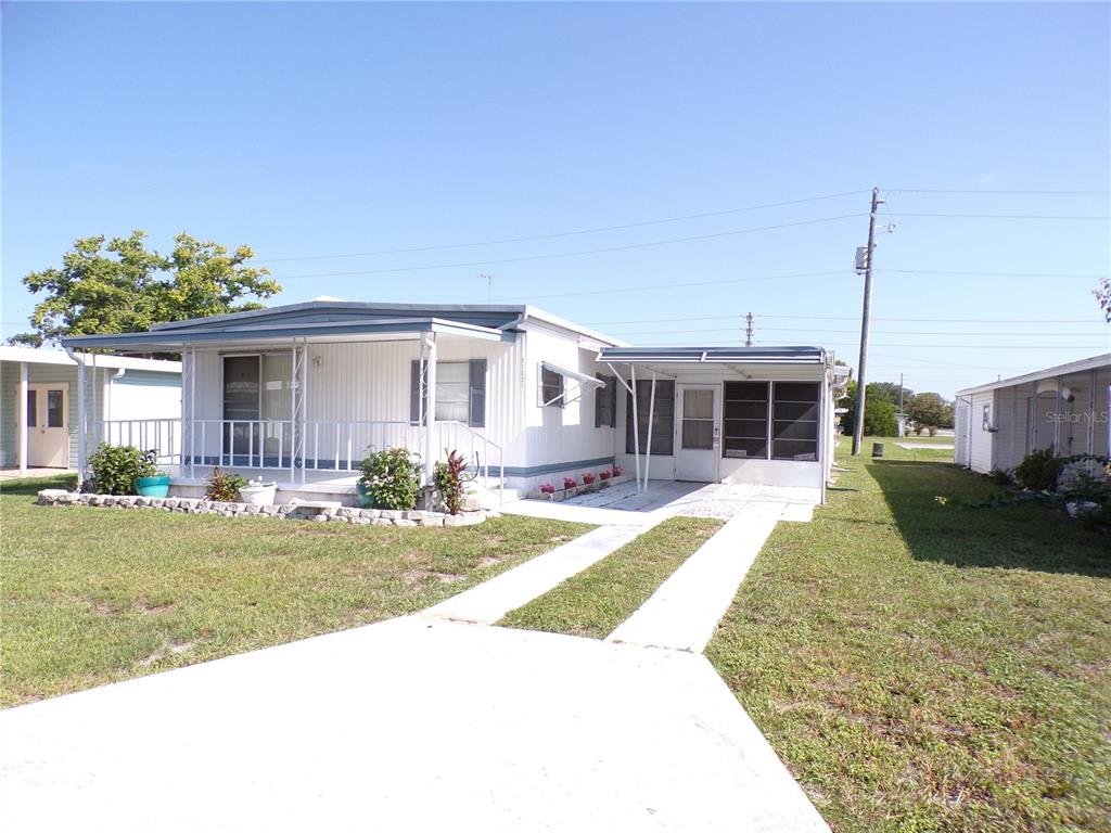A single-story manufactured home features a white exterior, a front porch, and a concrete driveway — 37021 SANDRA AVENUE, ZEPHYRHILLS, FL