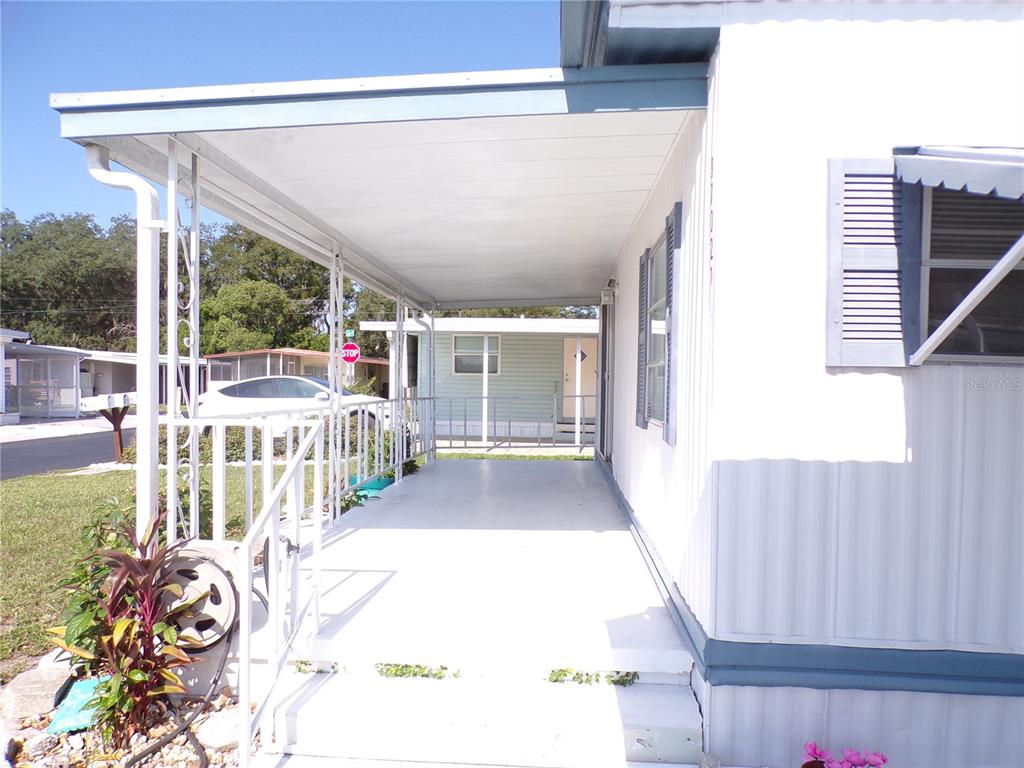 A covered porch with white railings and siding extends along the side of a home — 37021 SANDRA AVENUE, ZEPHYRHILLS, FL