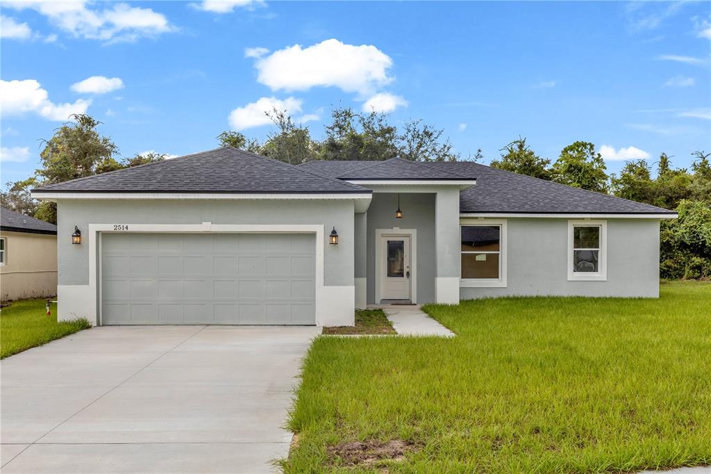 A single-story house with a gray stucco exterior, a two-car garage, and a concrete driveway — 2514 MAXIMUS COURT, DELTONA, FL