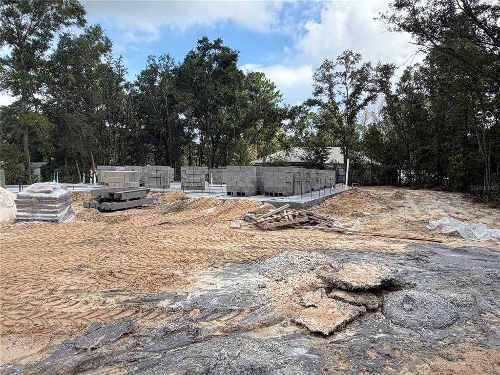 A construction site features a concrete foundation with stacked cinder blocks and piles of dirt — 9307 SE 159TH LANE, SUMMERFIELD, FL
