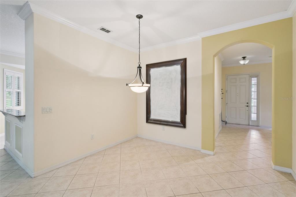 A dining area with tile flooring, a hanging light fixture, and a large framed mirror — 100 FLAME VINE WAY, GROVELAND, FL