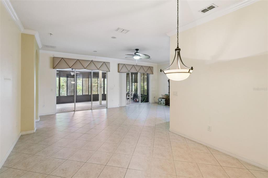 An open-concept living area features light-colored tile flooring, a ceiling fan, and sliding glass doors — 100 FLAME VINE WAY, GROVELAND, FL