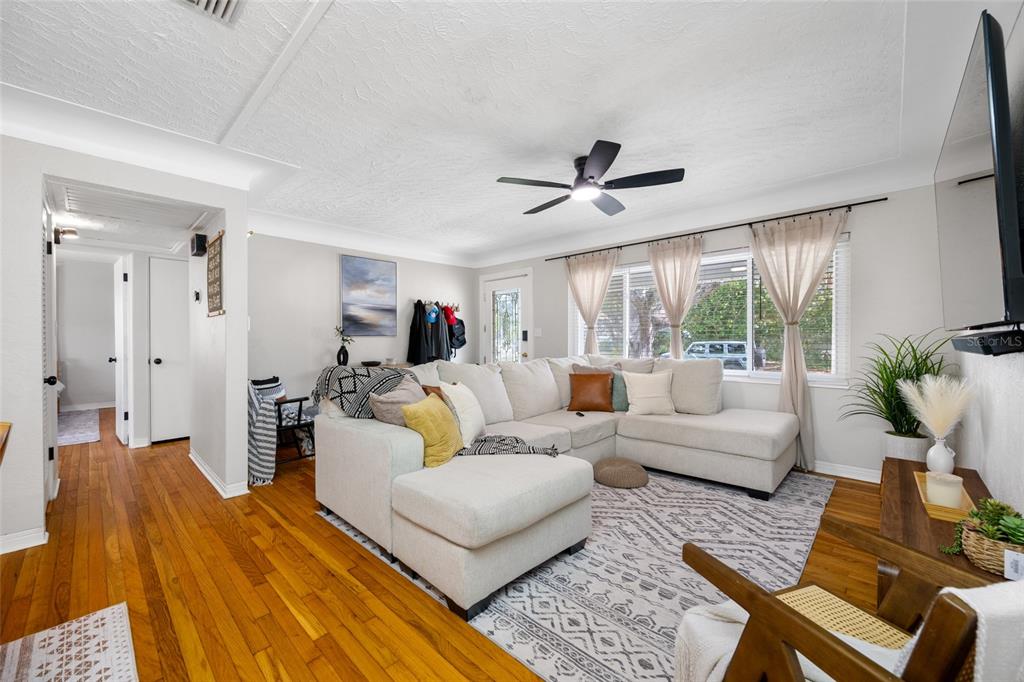 A living room features a large sectional sofa, hardwood floors, and a ceiling fan — 6219 HAMPTON DRIVE N, ST PETERSBURG, FL