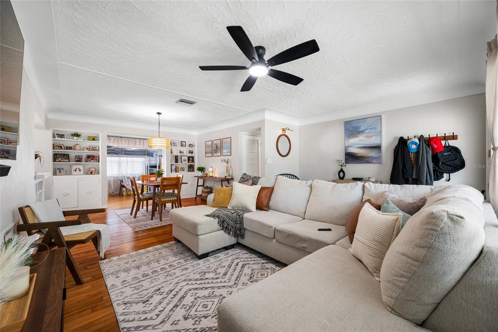 A living room features a large sectional sofa, hardwood floors, and an adjacent dining area — 6219 HAMPTON DRIVE N, ST PETERSBURG, FL