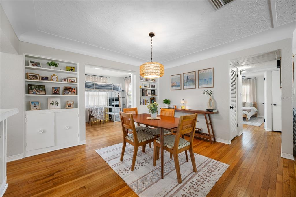 A dining room with a wooden table, chairs, built-in shelving, and hardwood floors — 6219 HAMPTON DRIVE N, ST PETERSBURG, FL