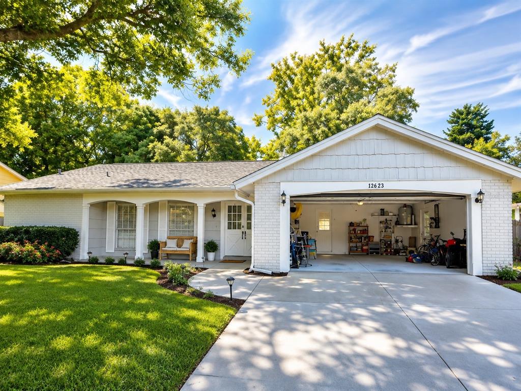 A single-story house with a white brick exterior, a front porch, and an attached garage — 12623 CLOCK TOWER PKWY, HUDSON, FL