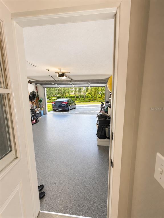 A view from a doorway into a garage with a gray epoxy floor and a car — 12623 CLOCK TOWER PKWY, HUDSON, FL