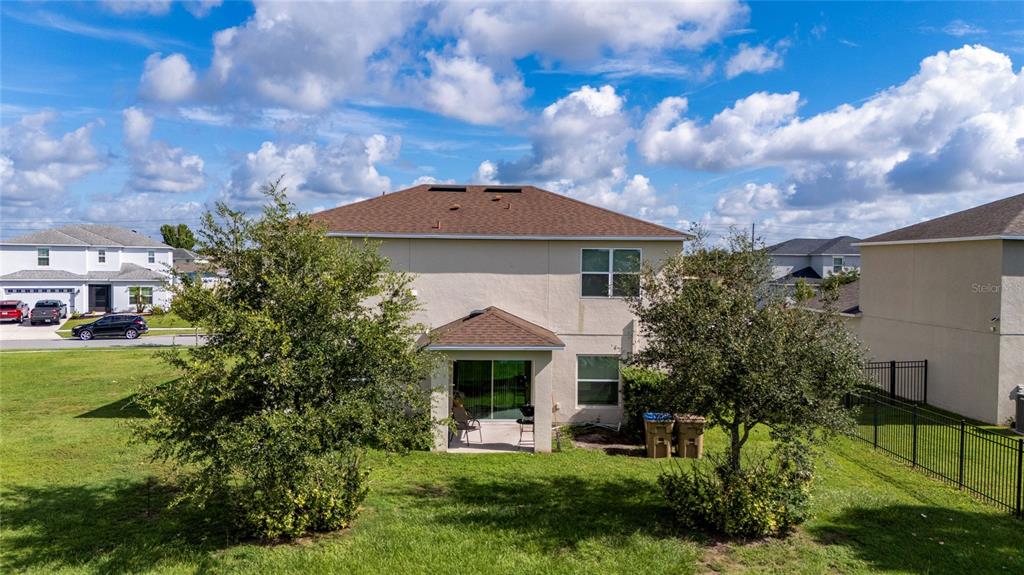 The rear exterior of a two-story house features a small patio and a grassy yard — 370 QUARRY ROCK CIRCLE, KISSIMMEE, FL