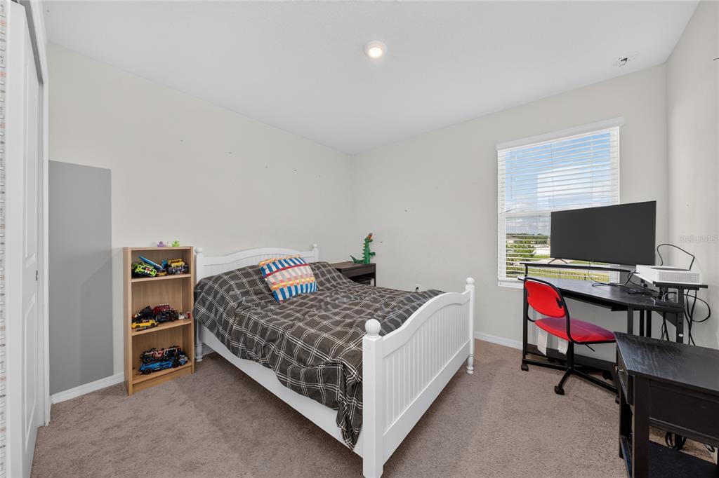 A bedroom with beige carpet, a white bed frame, a bookshelf, and a computer desk — 370 QUARRY ROCK CIRCLE, KISSIMMEE, FL