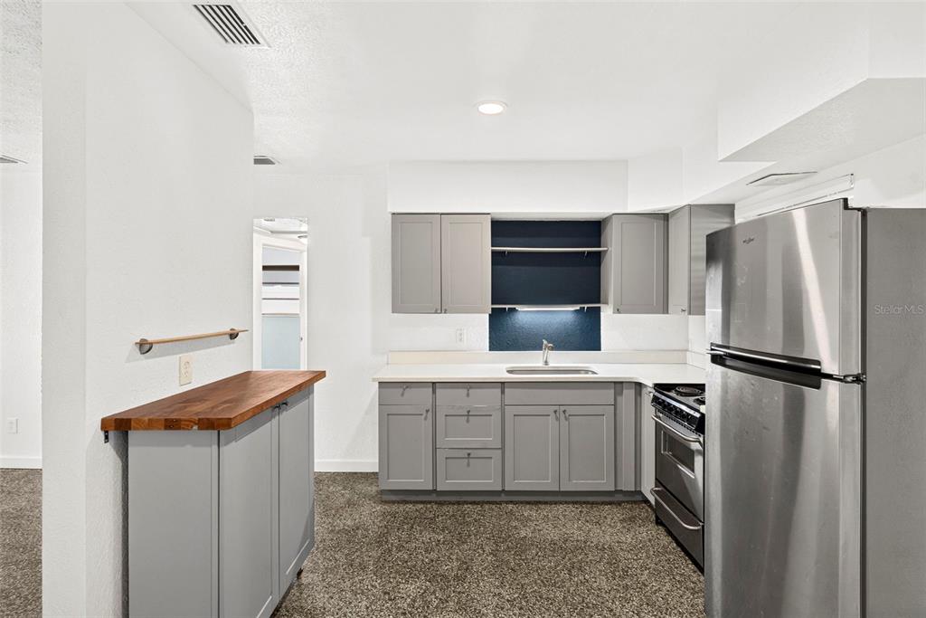 A kitchen features gray cabinets, a butcher block counter, and stainless steel appliances — 4501 26TH AVENUE S, ST PETERSBURG, FL