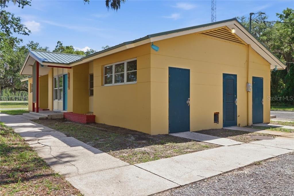 A yellow single-story building with a metal roof and three blue exterior doors — 18150 SE HIGHWAY 19, INGLIS, FL