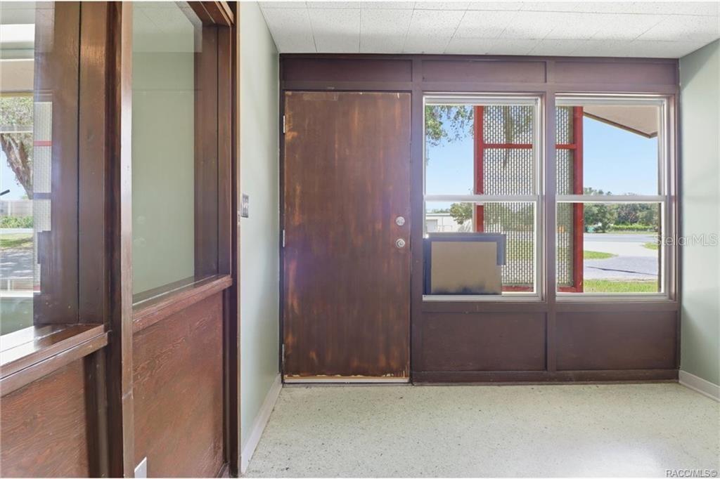 An interior entryway features a wooden door, large windows, and light-colored speckled flooring — 18150 SE HIGHWAY 19, INGLIS, FL