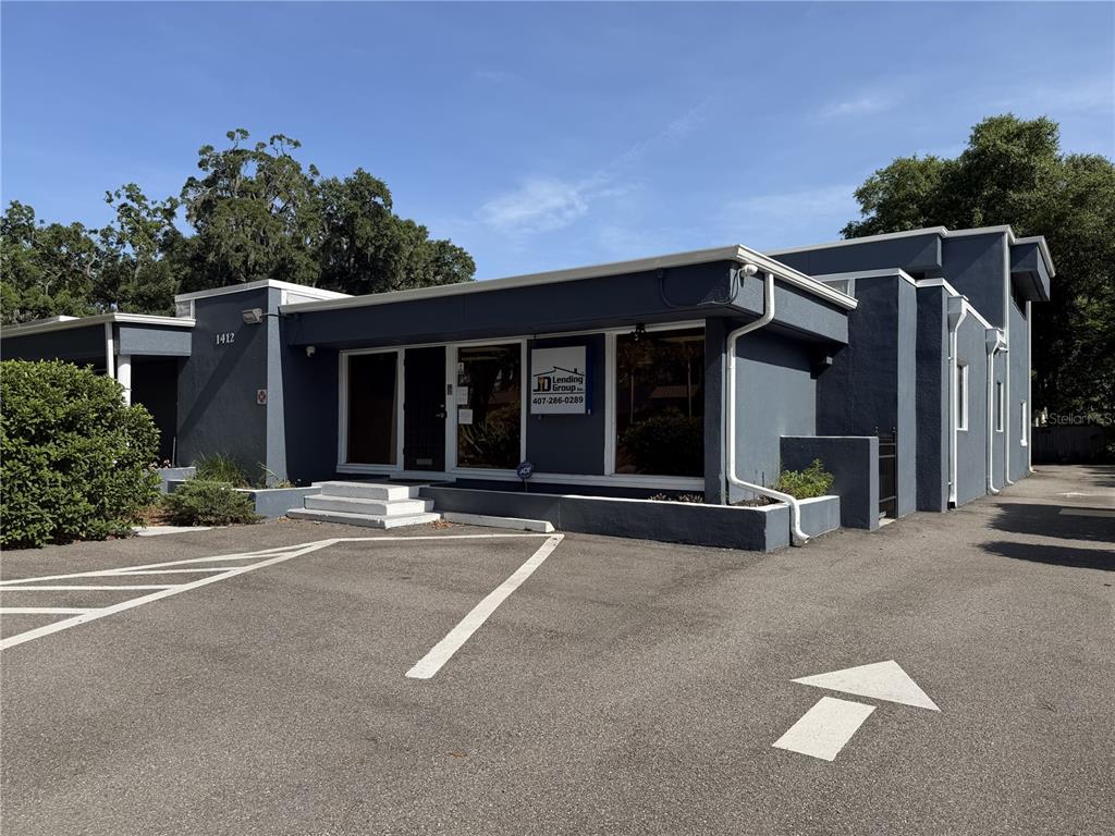 A gray commercial building with a parking lot and a white directional arrow on asphalt — 1404-1412 W COLONIAL DRIVE, ORLANDO, FL