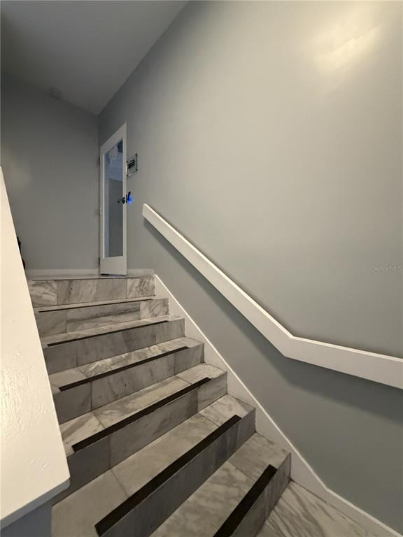 A staircase with marble-look tiled steps and a white handrail leads to a glass door — 1404-1412 W COLONIAL DRIVE, ORLANDO, FL