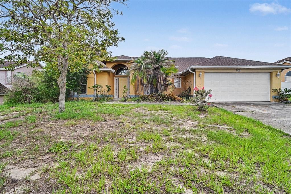A single-story house with a yellow stucco exterior, a two-car garage, and an overgrown lawn — 4716 SPANIEL STREET, ORLANDO, FL