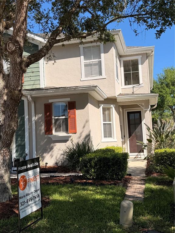 A two-story tan townhouse with a front yard, a brick walkway, and a real estate sign — 2219 PICO LANE, MOUNT DORA, FL