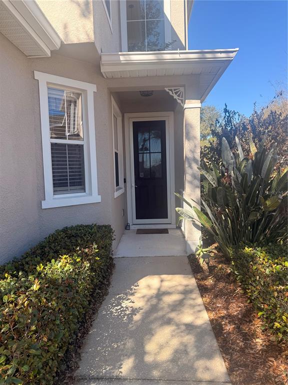 A concrete walkway leads to the front entrance of a house with a dark door — 2219 PICO LANE, MOUNT DORA, FL