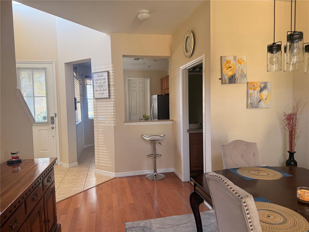 An interior view shows a dining area with wood floors, a breakfast bar, and entryway — 2219 PICO LANE, MOUNT DORA, FL