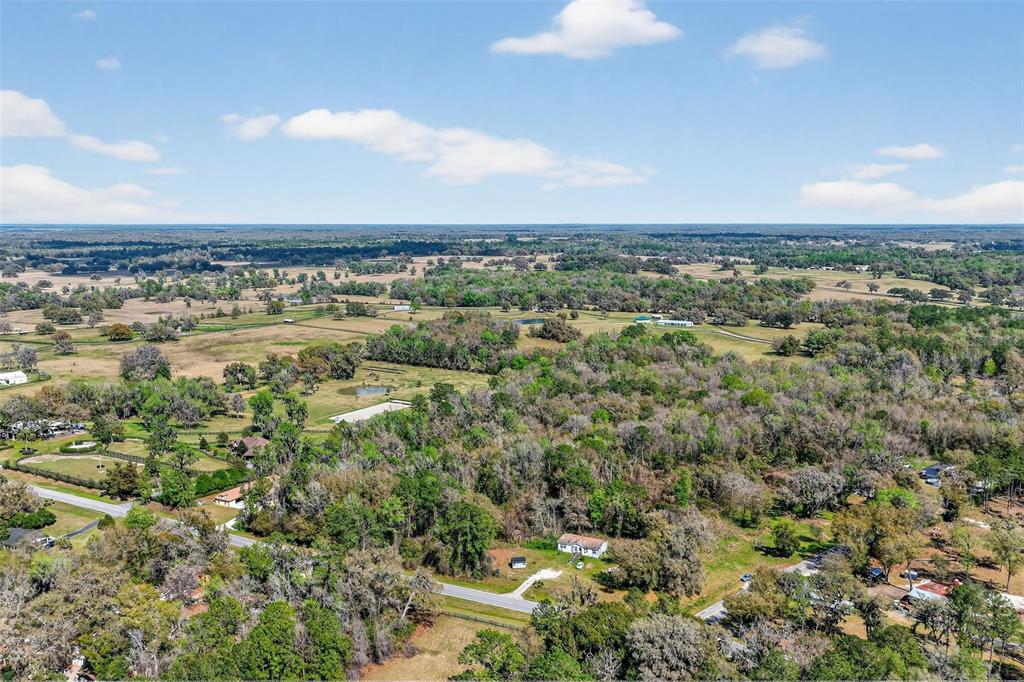 An aerial view shows a rural landscape with scattered houses, trees, and open fields — TBD NW HWY 225A, REDDICK, FL