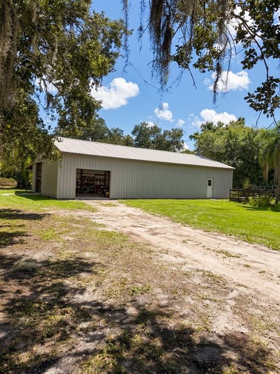 A large metal workshop building stands on a grassy lot with a dirt driveway — 3030 SE HIGHWAY 31, ARCADIA, FL