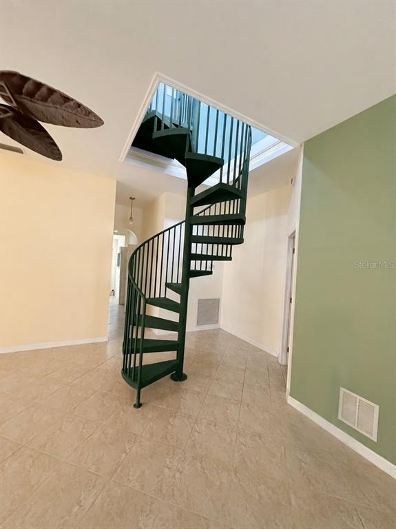 A dark green metal spiral staircase stands in a room with light-colored tile flooring — 3030 SE HIGHWAY 31, ARCADIA, FL
