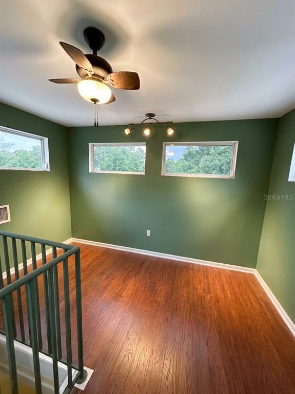 An upstairs room features green walls, wood-look flooring, a ceiling fan, and a metal railing — 3030 SE HIGHWAY 31, ARCADIA, FL