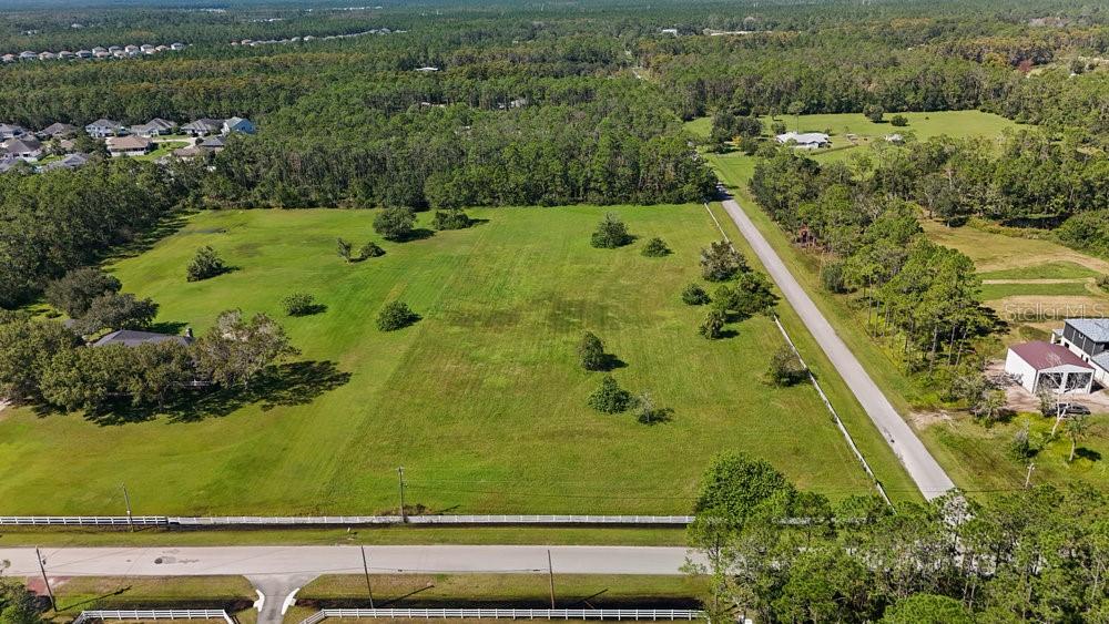 An aerial view shows a large, grassy, rectangular vacant lot bordered by trees and roads — 420 LEEWAY TRAIL, ORMOND BEACH, FL