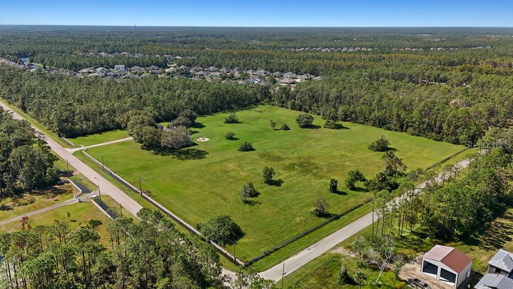 An aerial view shows a large, fenced grassy lot with scattered trees and a house — 420 LEEWAY TRAIL, ORMOND BEACH, FL